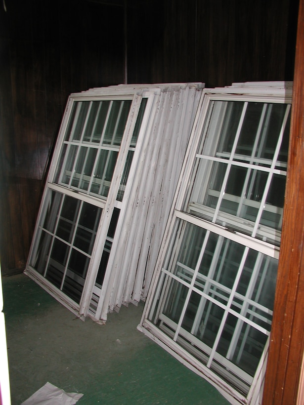 Windows that have been removed from a building are stacked and saved for sale or reuse.