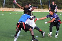 Devin Harris, 90th Maintenance Operations Squadron, stretches to gain extra yards while two defensemen pull at his flags Oct. 17, 2015, during the Rocky Mountain Flag Football Championship Game at the U.S. Air Force Academy, Colo. Each year, five tournaments are held in different sports to determine the winning teams. The next tournament is basketball. (U.S. Air Force photo by Senior Airman Brandon Valle)