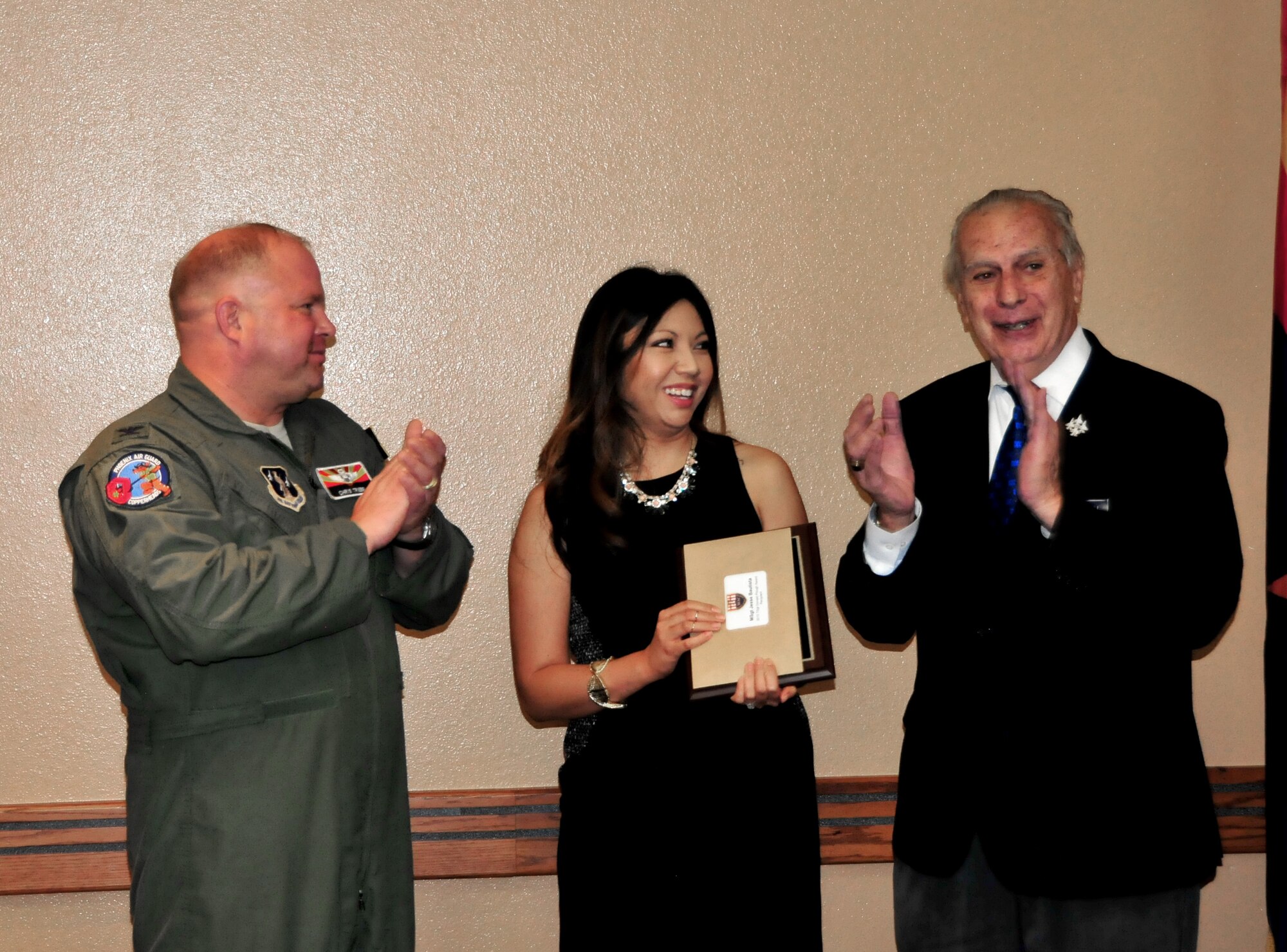 U.S. Air Force Col. Chris Triebel, 161st Air Refueling Wing vice commander, and Edward Scannell, Tempe Military Affairs Committee chair, present the Tech. Sgt. Donald Plough award to Jocelyn Bautista on behalf of her husband Master Sgt. Jesse Bautista during a ceremony Oct. 14, 2015,  at the wing.  Bautista is currently attending in-residence Senior Non-commissioned Officer Academy at Maxwell Air Force Base, Ala.  (U.S. Air National Guard photo by Master Sgt. Kelly Deitloff) 