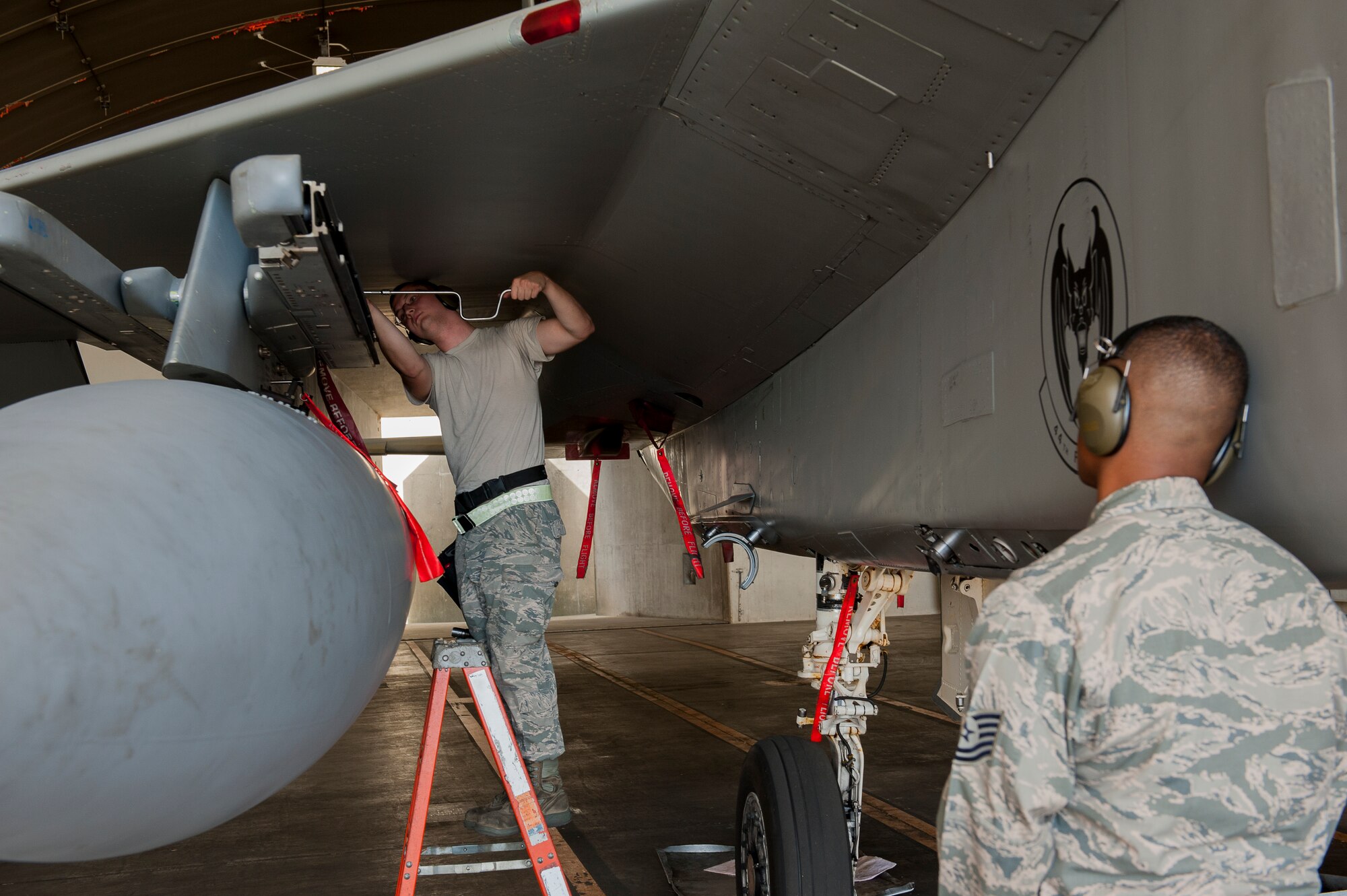 U.S. Air Force Senior Airman John Viktor Non, 67th FS weapons load crew member, works on the LAU-128 launcher while Tech. Sgt. Marquette Price, 18th Maintanence Group weapons standardization crew, supervises to ensure the process is done correctly and safely during a weapons loading competition on Kadena Air Base, Japan, Oct. 19, 2015. The competition tests the team's ability to load weapons on an F-15C Eagle in a realistic training environment. (U.S. Air Force photo by Airman Zackary A. Henry)