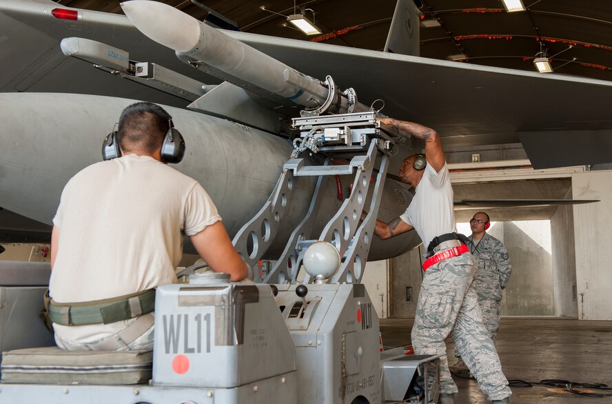 U.S. Air Force Staff Sgt. Craig Harrison, 67th Fighter Squadron weapons load crew chief, secures a LAU-128 missile with Airman 1st Class Brandon Myers, 67th FS weapons load crew member, during a weapons loading competition on Kadena Air Base, Japan, Oct. 19, 2015. The weapons load competition is a tradition held to raise morale, give airmen motivation to outperform their peers and set a higher standard for crews to come. (U.S. Air Force photo by Airman Zackary A. Henry)