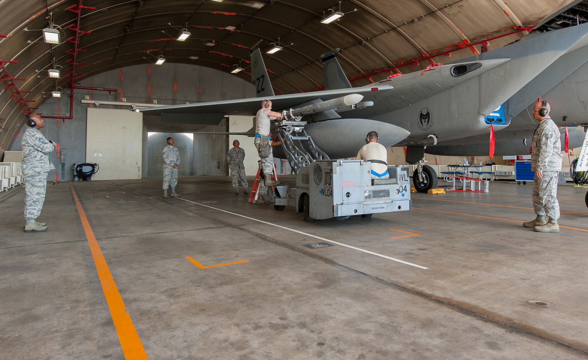 A weapons load crew team from the 44th Fighter Squadron works together to load a LAU-128 missile while the weapons standardization team supervises to ensure the process is done correctly and safely during a weapons loading competition on Kadena Air Base, Japan, Oct. 19, 2015. Competitions promote teamwork and provide realistic training among weapons load crews. (U.S. Air Force photo by Airman Zackary A. Henry)