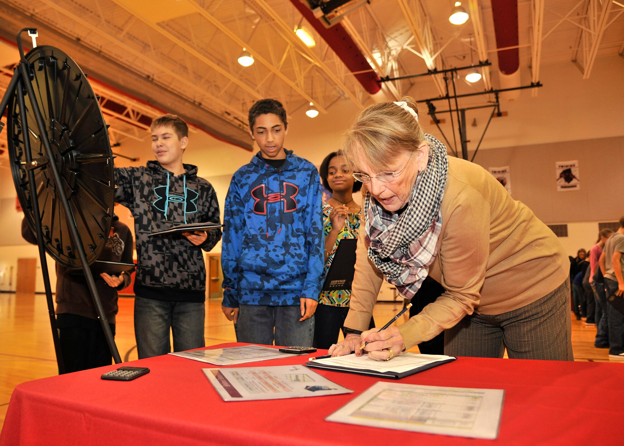 Sue Westerh, Service Credit Union Assistant Vice President for member services, deducts money from a student from Nathan Twining Elementary and Middle School during the Credit Union 4 Reality fair Oct. 16, 2015, on Grand Forks Air Force Base, North Dakota. The concept of the fair is to engage students on smart money decisions. (U.S. Air Force photo by Senior Airman Xavier Navarro/Released)