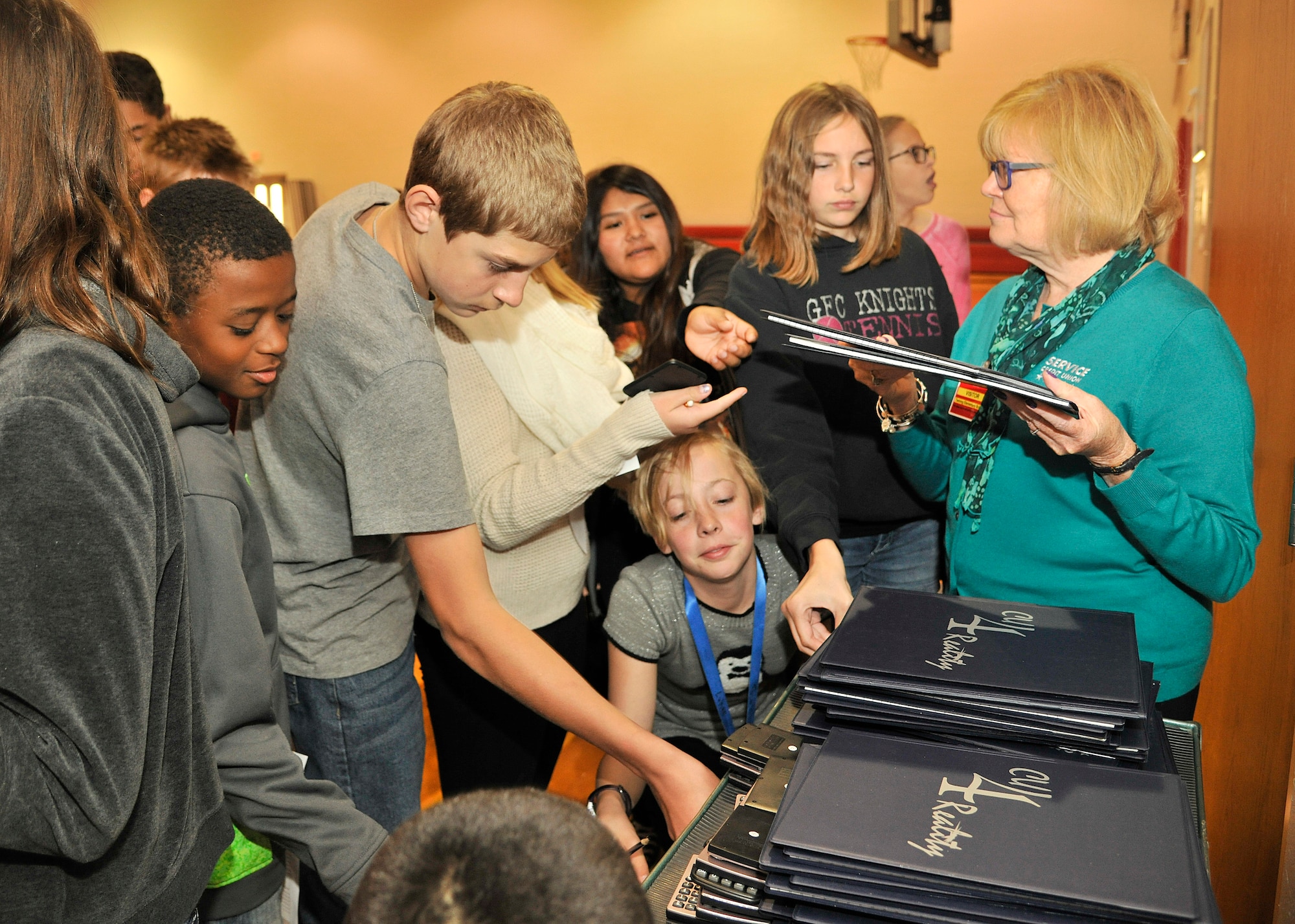 Seventh grade students gather up around a pick-up station to get their personal documents during the Credit Union 4 Reality fair at Nathan Twining Elementary and Middle School Oct. 16, 2015, on Grand Forks Air Force Base, North Dakota. Students had to make life decisions such as buying essential things in life versus wants. (U.S. Air Force photo by Senior Airman Xavier Navarro/Released)