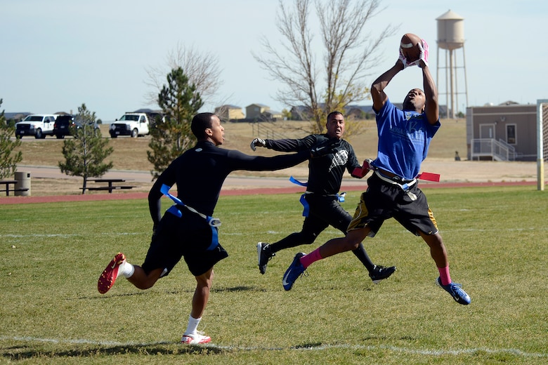 Tony Strickland, 4th Space Operations Squadron, makes a leaping catch between two 50th Security Forces Squadron defenders during the intramural flag football championship game at Schriever Air Force Base, Colorado, Thursday, Oct. 15, 2015. Strickland, who took the catch 42 yards for a touchdown, also returned an interception for a touchdown to lead 4 SOPS to a 25-0 victory. (U.S. Air Force photo/Christopher DeWitt) 