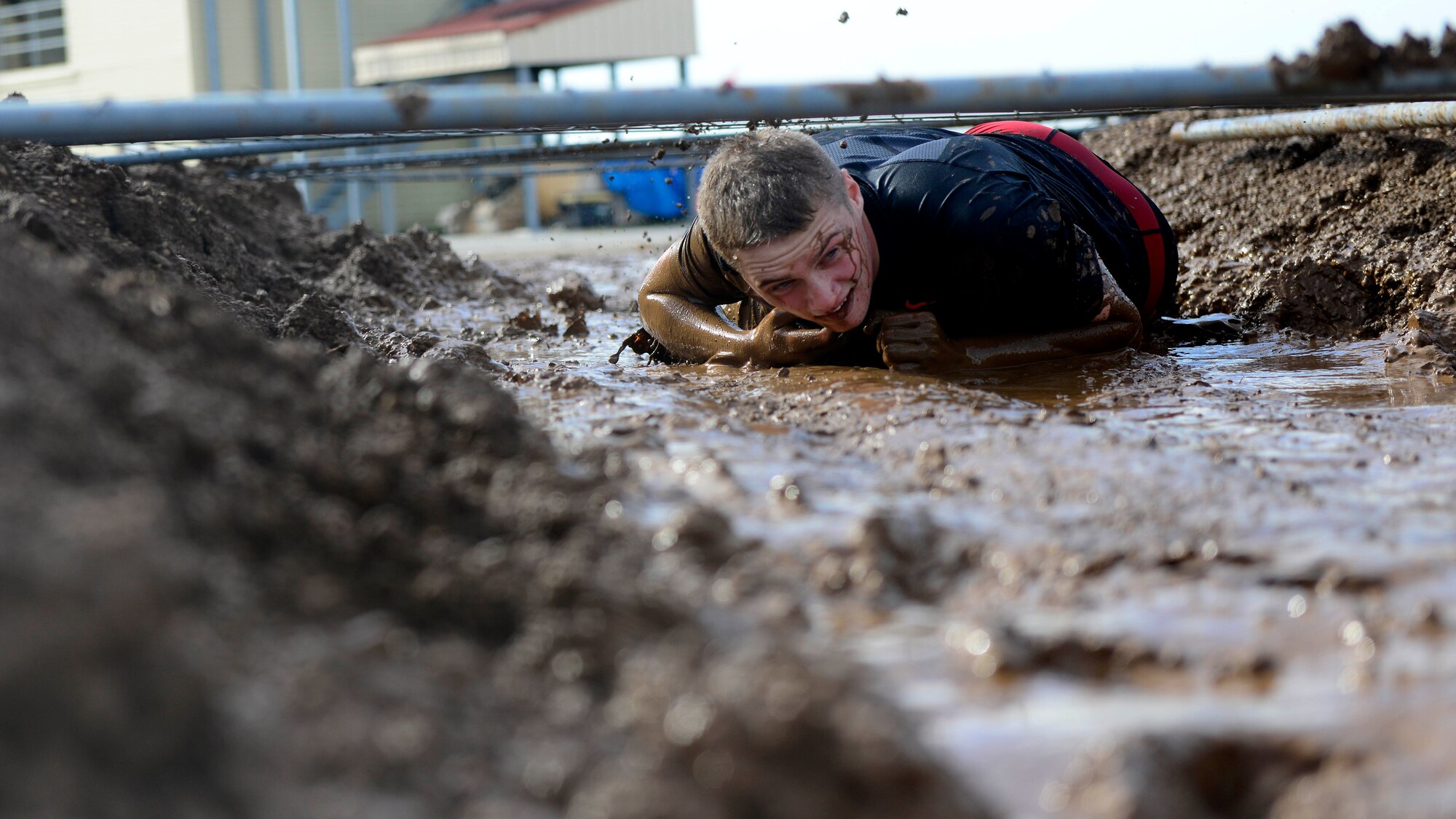 U.S. Air Force Airman 1st Class Joseph Lyon, 31st Munitions Squadron armament team member, crawls through a mud lane during the Wyvern Mud Run, Oct. 17, 2015, at Aviano Air Base, Italy. The six-mile course included 400,000 pounds of mud and more than 12 obstacles, such as T-walls, low crawls and tire flips. (U.S. Air Force photo by Senior Airman Areca T. Bell/Released)