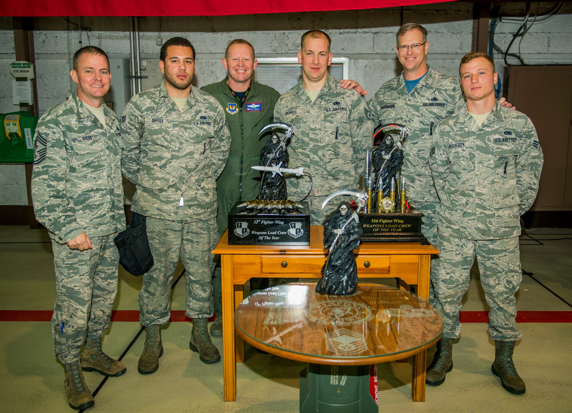 U.S. Air Force Chief Master Sgt. Brian Gates, 52nd Fighter Wing command chief, far left, U.S. Air Force Senior Airman Jonathan Rivera, a 480th Fighter Squadron weapons crew member of the winning team for the quarterly weapon load competition, U.S. Air Force Col. Joe McFall, 52nd FW commander, U.S. Air Force Staff Sgt. Joseph Morris, a 480th FS weapons team chief, U.S. Air Force Craig Brandenburg, 52nd Maintenance Group wing weapons manager, and U.S. Air Force Senior Airman Travis Dougherty, a 480th weapons crew member, far right, pose for a photo after the competition in Hangar 1 on Spangdahlem Air Base, Germany, Oct. 16, 2015. The competition tested the accuracy and speed of the Maintenance Airmen’s loading capabilities. The competition required team members to safely secure the dummy weapons, load them onto a miniature transportation unit and attach them safely onto the wings of an F-16 Fighting Falcon fighter aircraft. (U.S. Air Force photo by Airman 1st Class Timothy Kim/Released) 