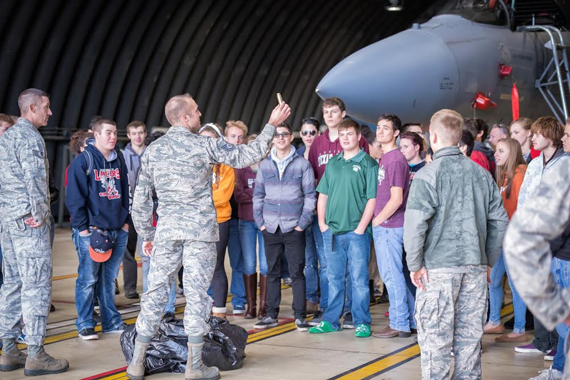 Tech. Sgt. Nicholas Sinnwell, 748th Aircraft Maintenance Squadron airframe and power plant generalist section chief, shows a 20mm round casing to Lakenheath High School seniors at Royal Air Force Lakenheath, England, Oct. 14, 2015, during their educational field trip to learn about the mission of the 48th Fighter Wing. The event brought Airmen and the children of military service members together, taking advantage of a great opportunity to share information and bring a better understanding to the students of what their parents roles are as Airmen. (U.S. Air Force photo by Tech. Sgt. Derek Revella/Released)