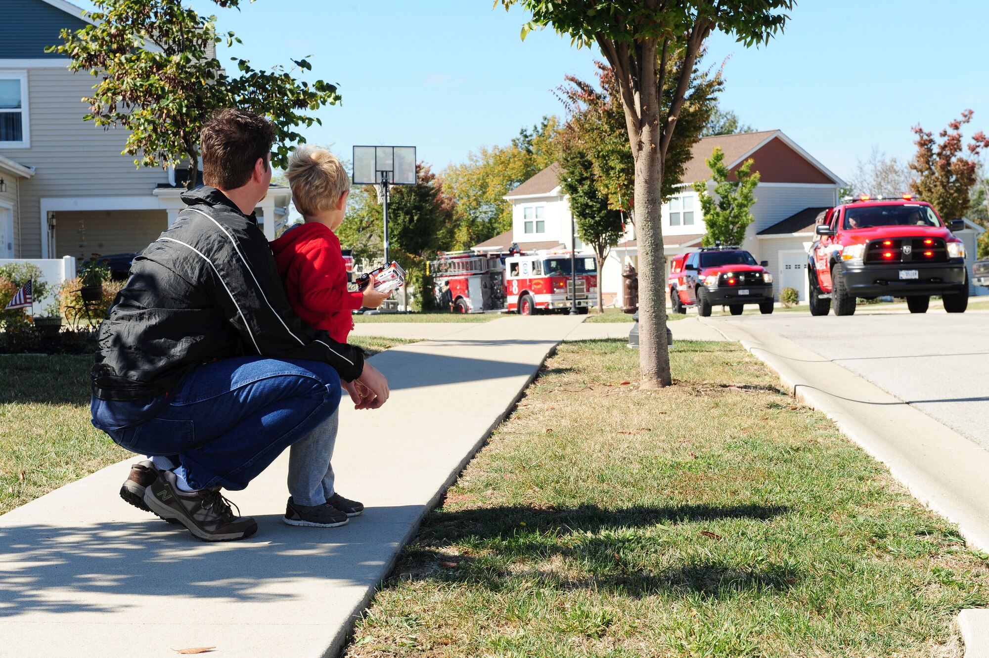 Base residents line the sidewalks to witness the annual Fire Prevention Parade Oct. 10, 2015, at Whiteman Air Force Base, Mo.  Fire trucks from Whiteman and the local communities drove around base with Smokey the bear, Sparky the dog and J.B. the fireman and greeted residents with handfuls of candy.  Following the parade, the Whiteman Fire Department hosted activities in the commissary parking lot which carried a theme of teaching how to prevent and respond to fires in the home. (U.S. Air Force photo by Airman 1st Class Jazmin Smith)