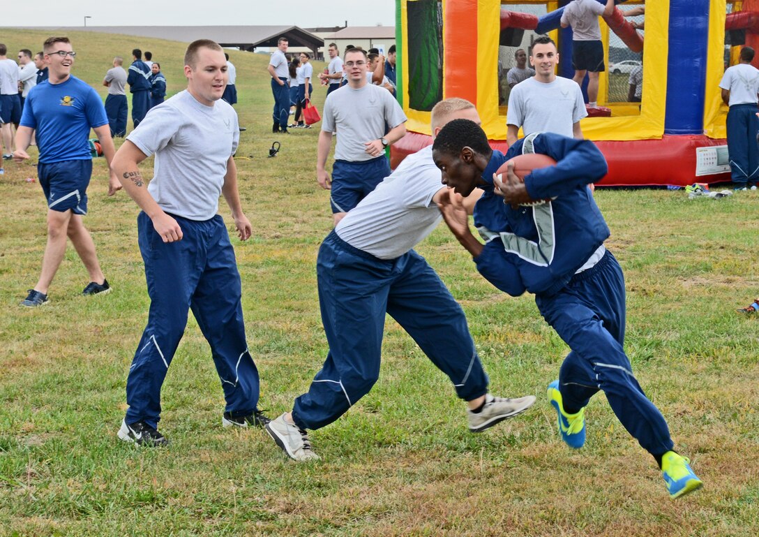 U.S. Air Force Airman 1st Class Casey Green, 509th Bomb Wing Judge Advocate paralegal journeyman, runs past defenders during a football game on Wingman Day, Oct. 9, 2015 at Whiteman Air Force Base, Mo. Events were held throughout the day to strengthen and sustain a resilient Air Force community that values mental, physical, social and spiritual fitness. (U.S. Air Force photo by Tech. Sgt. Miguel Lara III/Released)