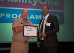 Navy Rear Adm. John King, DLA land and Maritime commander, presents Steve Ogletree a certificate of appreciation Oct. 7 inside the Building 20 auditorium during AbilityOne Day. Ogletree, who works at Cincinnati Association for the Blind and Visually impaired, told his story of overcoming his disability to achieve success in life.