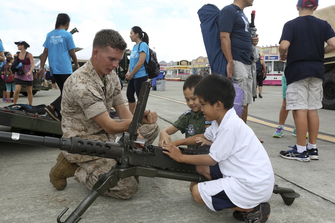 A Marine demonstrates how to hold the charging handle of an M2 Browning .50 caliber machine gun as he talks to schoolchildren about the weapon during a display at the Kaneohe Bay Air Show at Marine Corps Base Hawaii, Oct. 16. 2015. U.S. Marine Corps photo by Cpl. Ricky S. Gomez