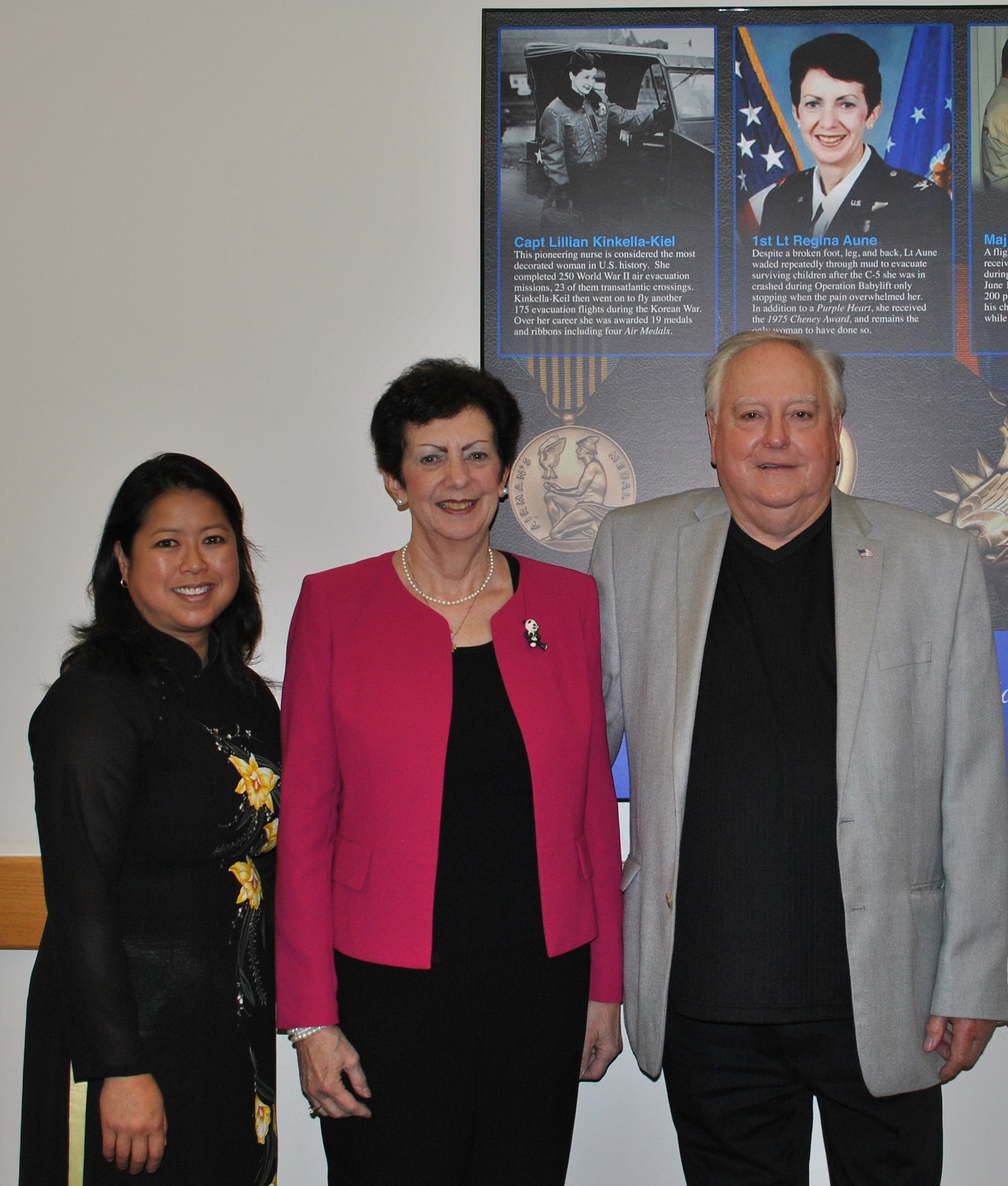 Aryn Lockhart (from left), retired Lt. Col. Regina C. Aune and retired Chief Master Sgt. Ray Snedegar stand in front of a piece of art honoring “Those Who Save,” which includes a tribute to then 1st Lt. Regina Aune. The artwork is in Building 1 at Joint Base San Antonio-Lackland, Texas. (U.S. Air Force photo/Carole Chiles Fuller/Released)