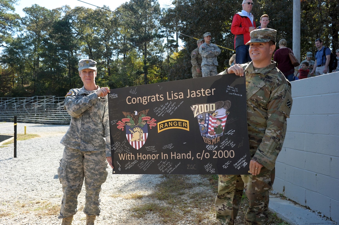 Friends of U.S. Army Maj. Lisa Jaster hold a sign of support during Ranger School graduation on Fort Benning, Ga., Oct. 16, 2015. Jaster is an Army reservist and one of three women to graduate from Ranger School. (U.S. Army photo by Staff Sgt. Alex Manne/ Released)