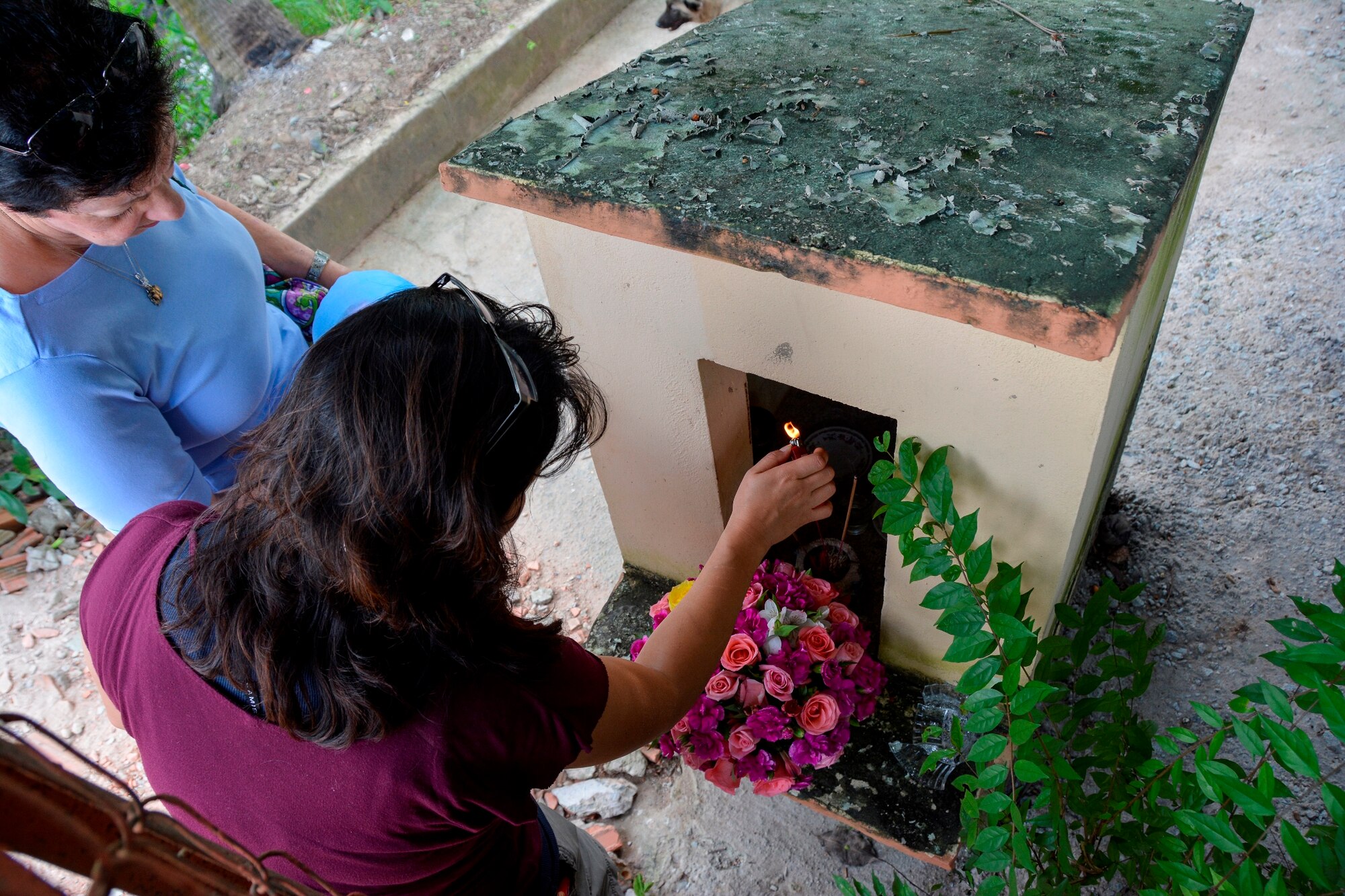 Operation Babylift survivor Aryn Lockhart, lights a memorial candle at a shrine commemorating those lost during the crash of a C-5A in Saigon, Vietnam, in April 1975. More than 70 orphans bound for the United States died in the crash.