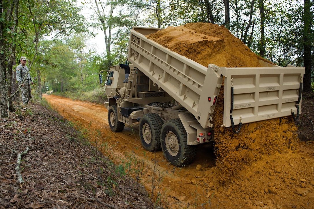 A South Carolina Army National Guardsman directs a dump truck to drop a load of clay dirt to rebuild a road that was washed out in Swansea, S.C., Oct. 13, 2015, after historic statewide flooding in early October. South Carolina Air National Guard photo by Tech. Sgt. Jorge Intriago