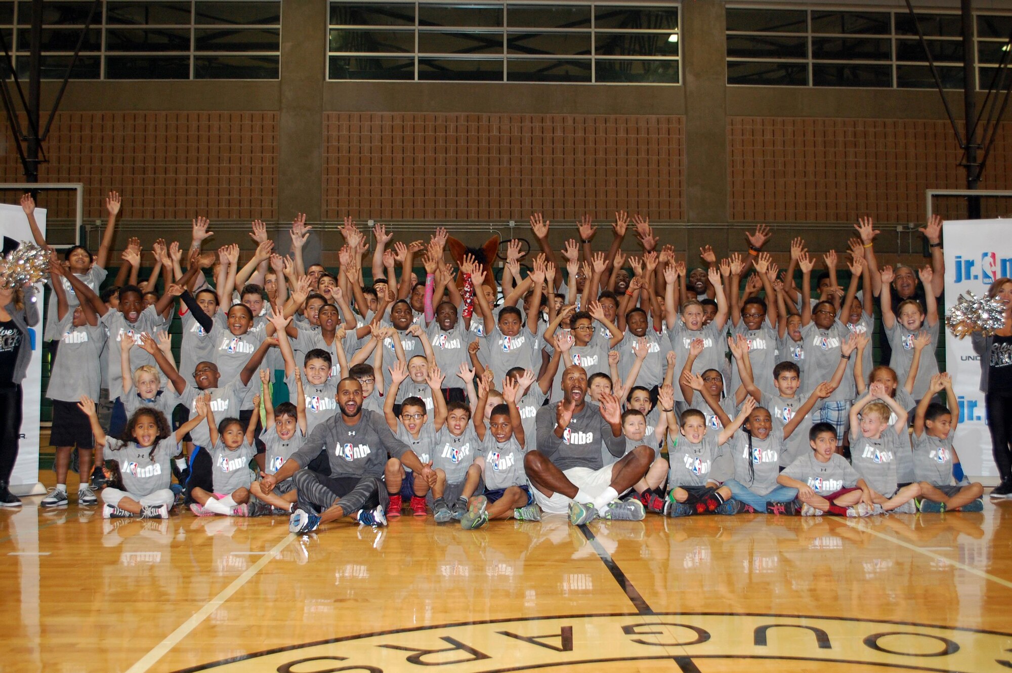 Spurs guard Patty Mills and NBA Legend Bruce Bowen, the Coyote, Silver Dancers and head clinician Frank Lopez join clinic participants for a group photo at the close of the Jr. NBA clinic Oct. 19 at Joint Base San Antonio-Fort Sam Houston. (U.S. Air Force photo/Carole Chiles Fuller/Released)