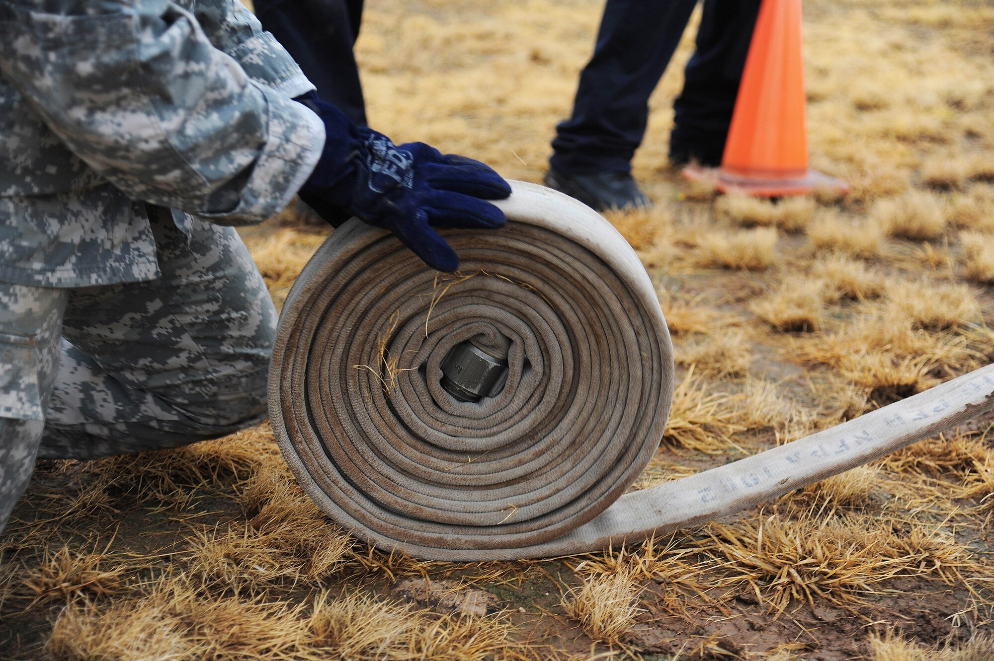 U.S Army Staff Sgt. Whitney Monts, 344th Military Intelligence Battalion platoon sergeant, rolls up a fire hose during the Annual Fire Muster Challenge beside the Fire Department at Goodfellow Air Force Base, Oct. 9, 2015. Officials docked points during the competition if the participants didn’t roll the fire hose up properly. (U.S. Air Force photo by Airman Caelynn Ferguson/Released)