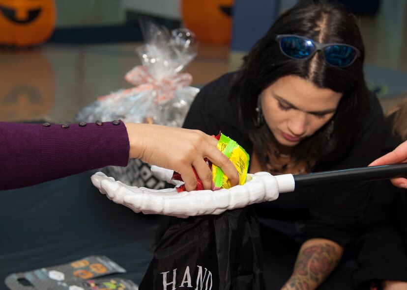 Candy is placed in a Halloween bag during the Deployed Families Dinner Oct. 15, 2015, at the Youth Center on Dover Air Force Base, Del. The Deployed Families Dinners allow spouses and children of deployed military members the opportunity to enjoy a meal, play games and receive information from base support agencies. (U.S. Air Force photo/Staff Sgt. Jared Duhon) 