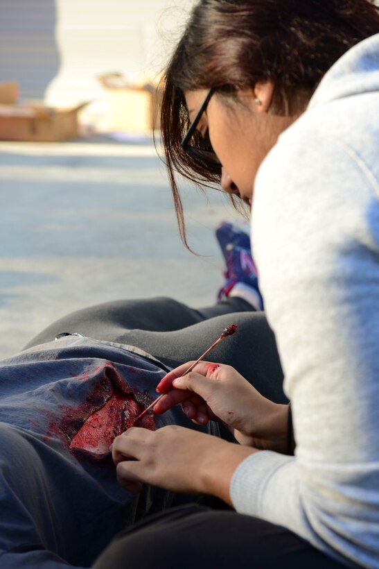U.S. Air Force Senior Airman Gloria Alqubaisi, 633rd Medical Group medical technician, applies moulage to an exercise victim during a medical mass casualty exercise at Langley Air Force Base, Va., Oct. 15, 2015. The exercise tested the ability to provide medical care to a simulated mass amount of casualties. (U.S. Air Force photo by Staff Sgt. Ciara Gosier/Released)