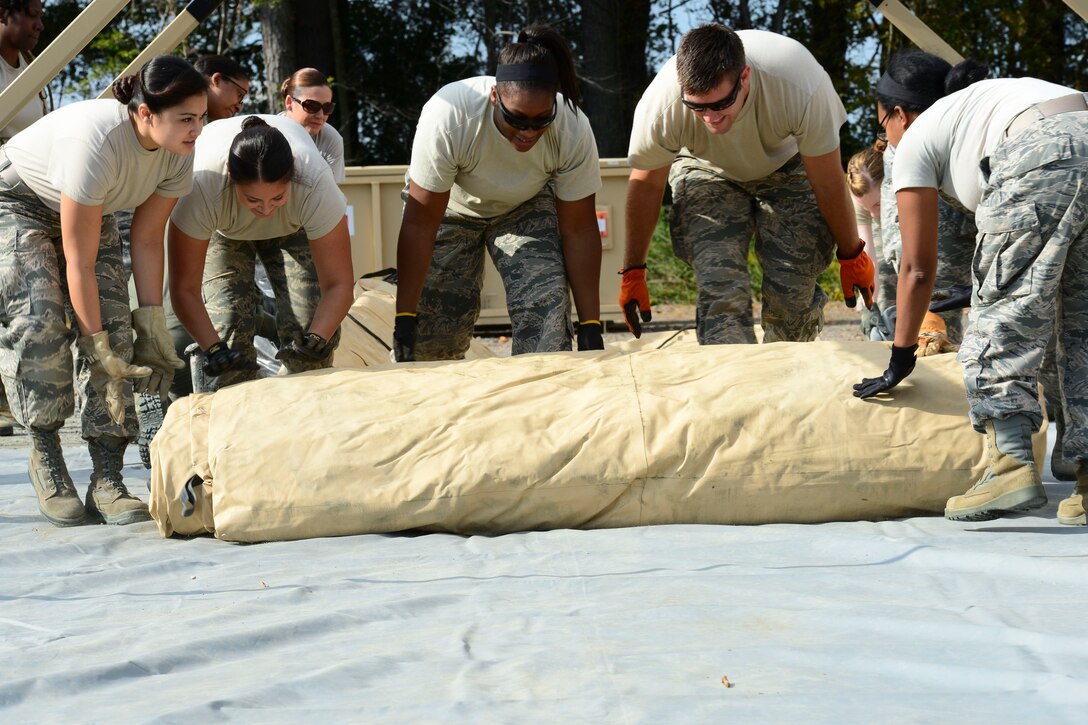 U.S. Air Force Airmen assigned to the 633rd Medical Group unroll a tent during set-up for a medical training exercise at Langley Air Force Base, Va., Oct. 13, 2015. The Airmen have to be able to quickly and decisively build a hospital in a deployed setting to care for patients in a timely manner. (U.S. Air Force photo by Staff Sgt. Ciara Gosier/Released)