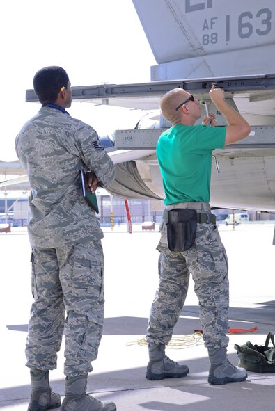 Tech. Sgt. Brandon Savage, 756th Aircraft Maintenance Squadron load crew chief, observes and judges the competition as Airman 1st Class Michael Roberts, 310th AMU load crew member, inspects an F-16 Fighting Falcon. (U.S. Air Force photo by A1C Ridge Shan)