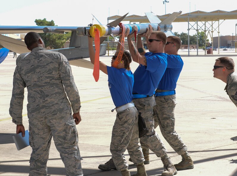 Airmen 1st Class Nadiya Frick and Joshua Lomax, and Staff Sgt. Timothy O’Brien, 309th AMU load crew members, load a missile onto an F-16. Crews from different units race to see which team can successfully load an F-16 first in the quarterly load crew competition. (U.S. Air Force photo by Airman 1st Class Ridge Shan)