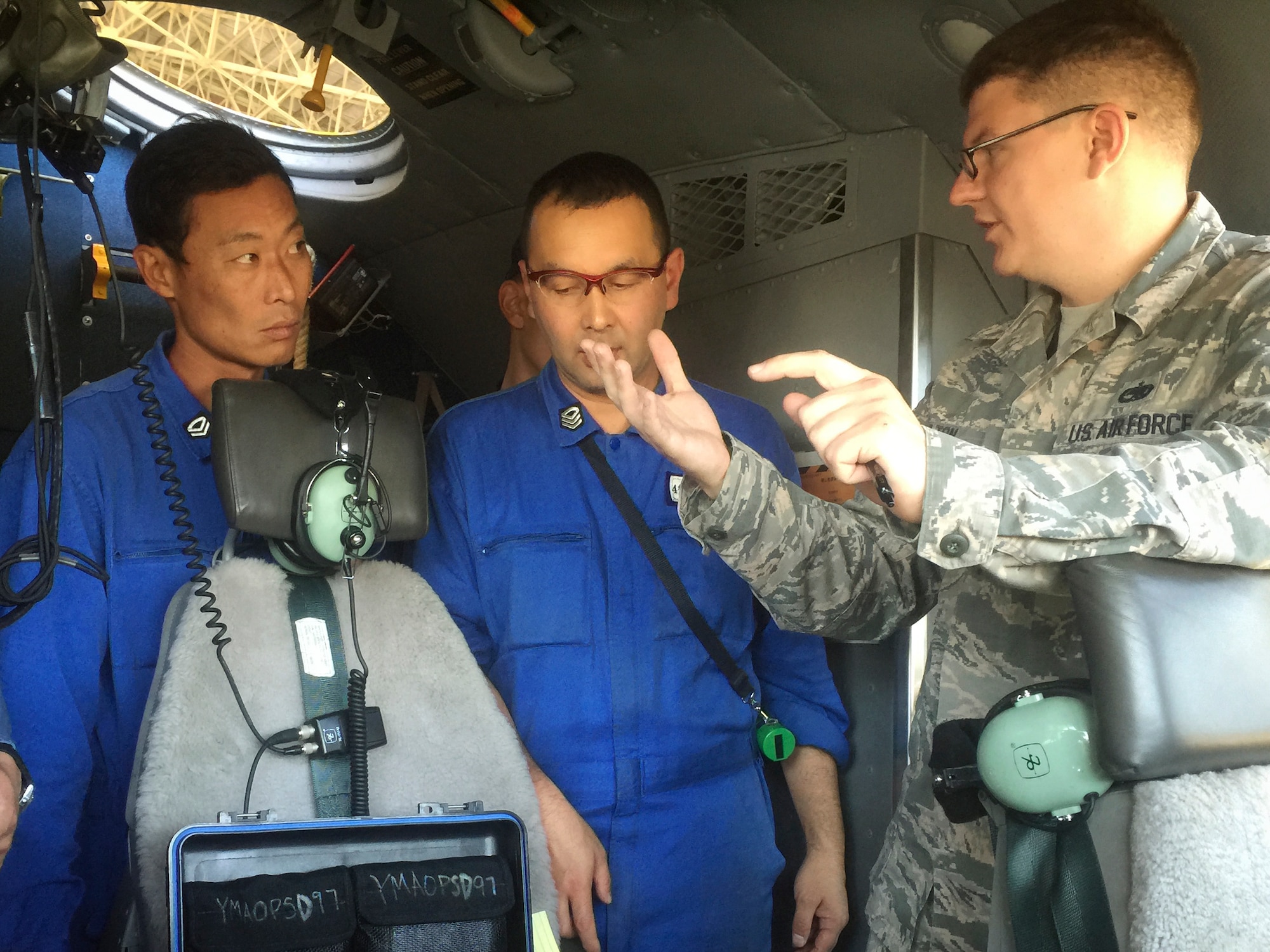 U.S. Air Force Tech. Sgt. Michael S. Hilton, 374th Aircraft Maintenance Squadron instrument and flight control craftsman, speaks with Japan Maritime Self-Defense Force members at Naval Air Facility Atsugi, Japan, Oct. 8, 2015. A total of three technicians flew to the  naval air facility to provide specialized test equipment and training to JMSDF maintenance personnel. (Courtesy photo by 374th Maintenance Group)