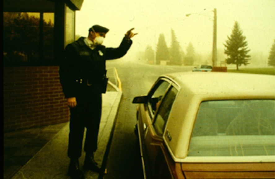 A security forces Airman directs traffic at the main gate while an ash cloud from the Mt. St. Helens eruption turns the sky yellow, May 18, 1980, at Fairchild Air Force Base, Wash. (courtesy photo)