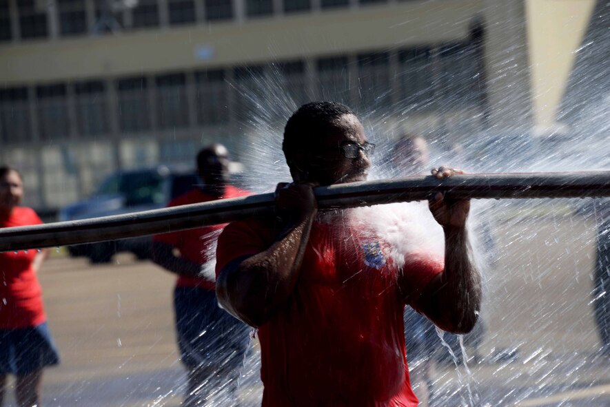 A Maxwell Airman hangs on to a water hose while being pelted with water during the 2015 Maxwell Fire Muster Oct. 16, 2015, at Maxwell Air Force Base, Ala. 28 teams of Airmen came together to compete during the base wingman day to enhance moral and camaraderie.(U.S. Air Force photo by Airman 1st Class Alexa Culbert).