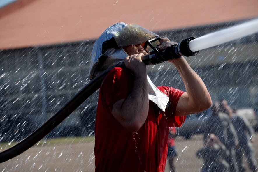 A Maxwell Airmen grips on to a water hose during the 2015 Maxwell Fire Muster Oct. 16, 2015, at Maxwell Air Force Base, Ala-a. The objective of the obstacle was to aim the hose at a suspended bucket and push it toward the opposing team. (U.S. Air Force photo by Airman 1st Class Alexa Culbert)