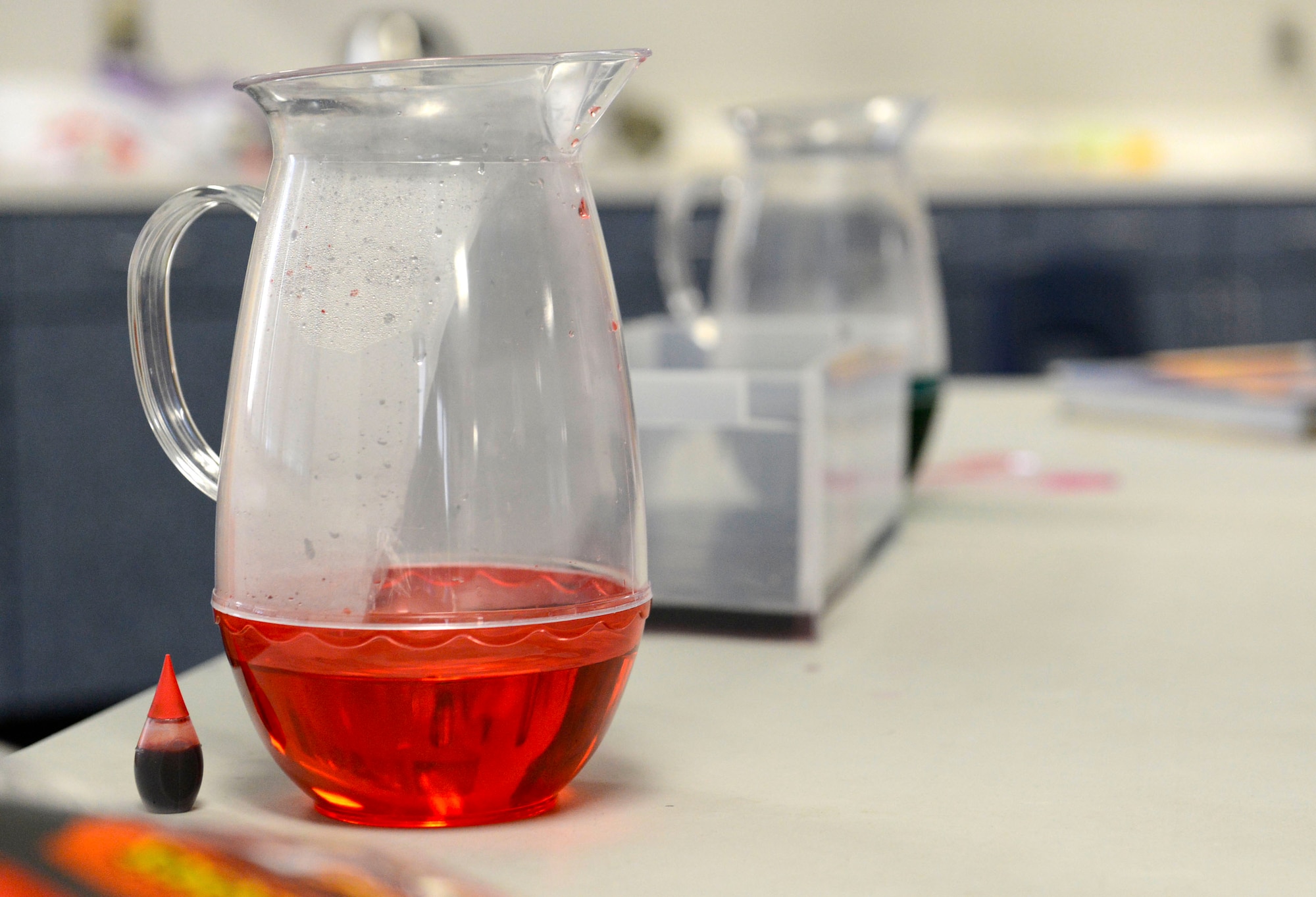 Weather forecasters assigned to the 20th Operation Support Squadron display a pitcher of hot, red water for students at Alice Drive Middle School, Sumter S.C., Oct. 15, 2015. The station consisted of hot red water and cold blue water which when mixed together simulates what happens in earth’s atmosphere in the event of a cold front.  (U.S. Air Force photo by Airman 1st Class Christopher Maldonado/Released)