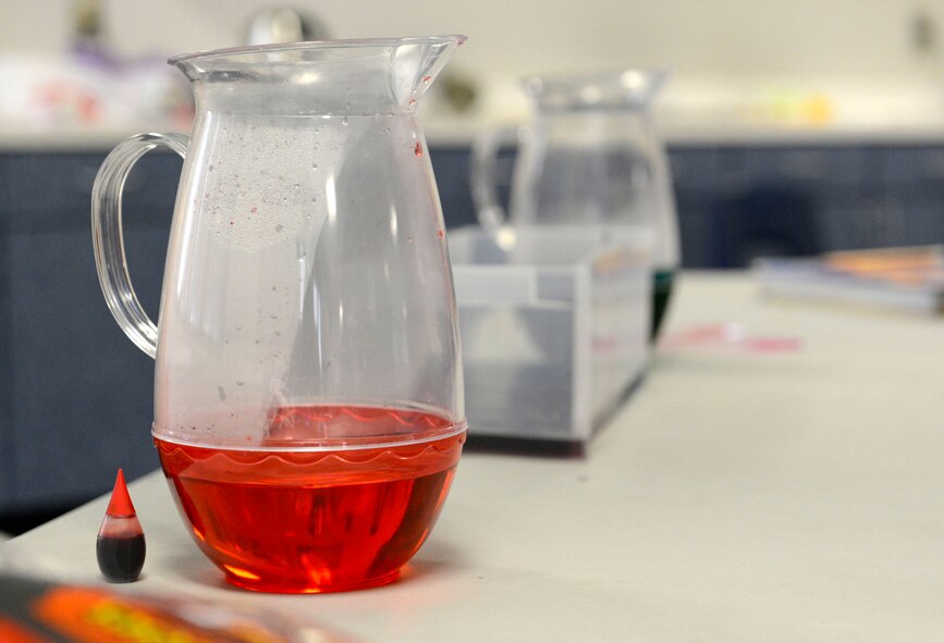 Weather forecasters assigned to the 20th Operation Support Squadron display a pitcher of hot, red water for students at Alice Drive Middle School, Sumter S.C., Oct. 15, 2015. The station consisted of hot red water and cold blue water which when mixed together simulates what happens in earth’s atmosphere in the event of a cold front.  (U.S. Air Force photo by Airman 1st Class Christopher Maldonado/Released)