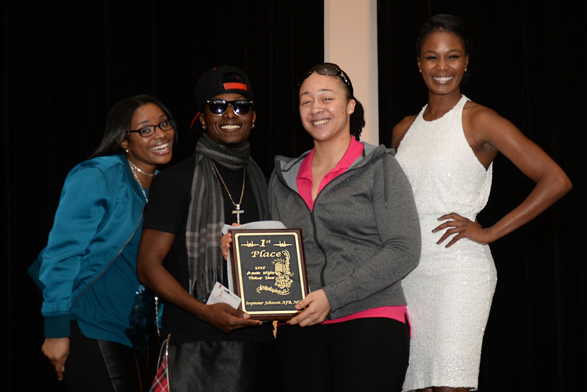 Senior Airman Nadiyah Bilal-Mitchell (center-right), 335th Fighter Squadron aviation resource management specialist, is presented the first place plaque at the conclusion of the base talent show, Oct. 16, 2015, at Seymour Johnson Air Force Base, North Carolina. After receiving the majority vote from the crowd, Bilal-Mitchell was awarded first place out of seven competitors. (U.S. Air Force photo/Airman 1st Class Ashley Williamson)