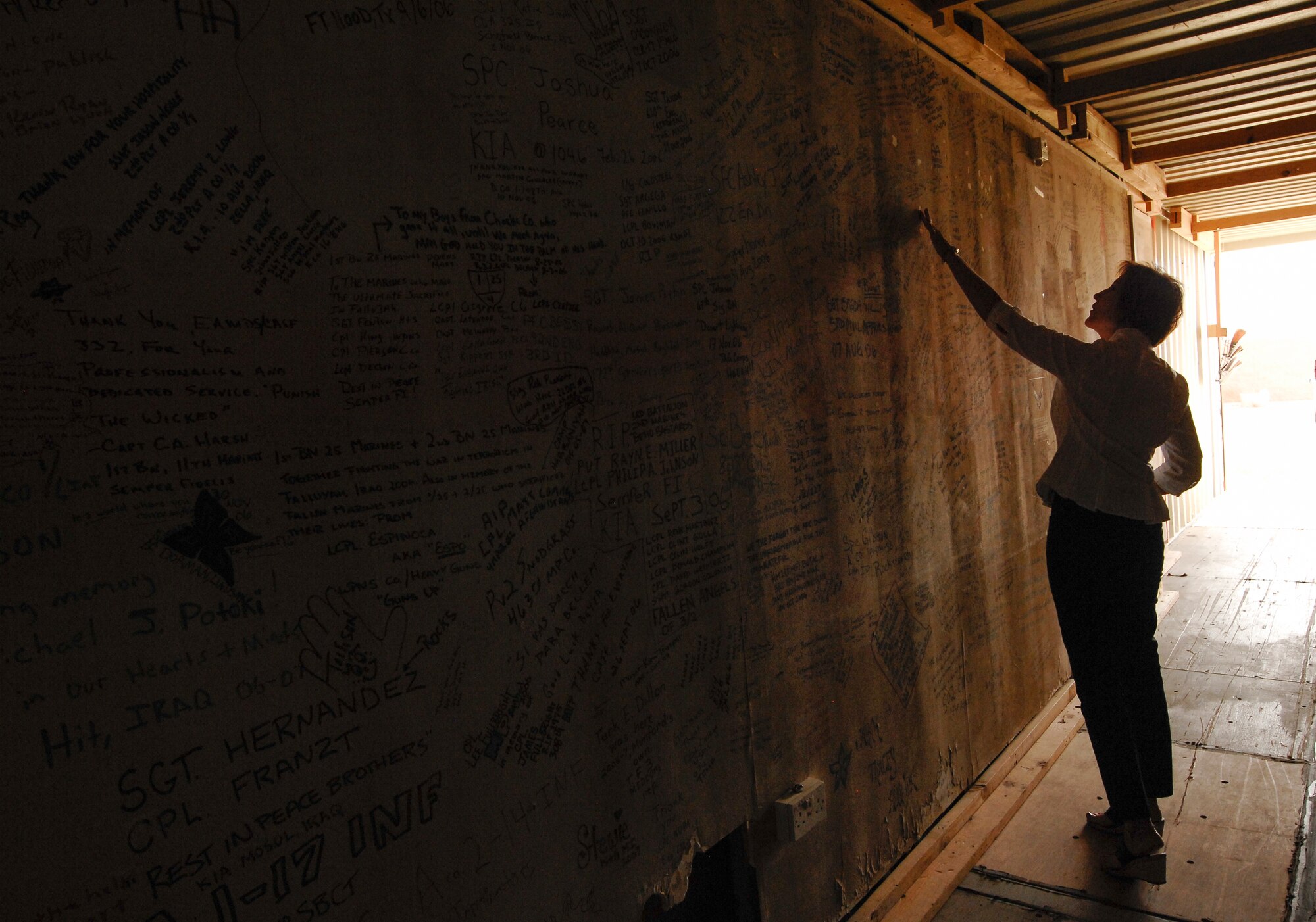 Retired U.S. Air Force Reserve Senior Master Sgt. Karen Loalbo touches the original Wall of Balad at the 309th Aerospace Maintenance and Regeneration Group, Davis-Monthan Air Force Base, Ariz., Oct. 16, 2015. Loalbo’s vision to start the Walls of Balad began in 2006, while deployed to the 332nd Expeditionary Medical Group Contingency Aeromedical Staging Flight facility at Joint Base Balad, Iraq. Patients and visitors of the CASF signed the walls until 2011, when it closed. (U.S. Air Force photo by Staff Sgt. Angela Ruiz/Released)
