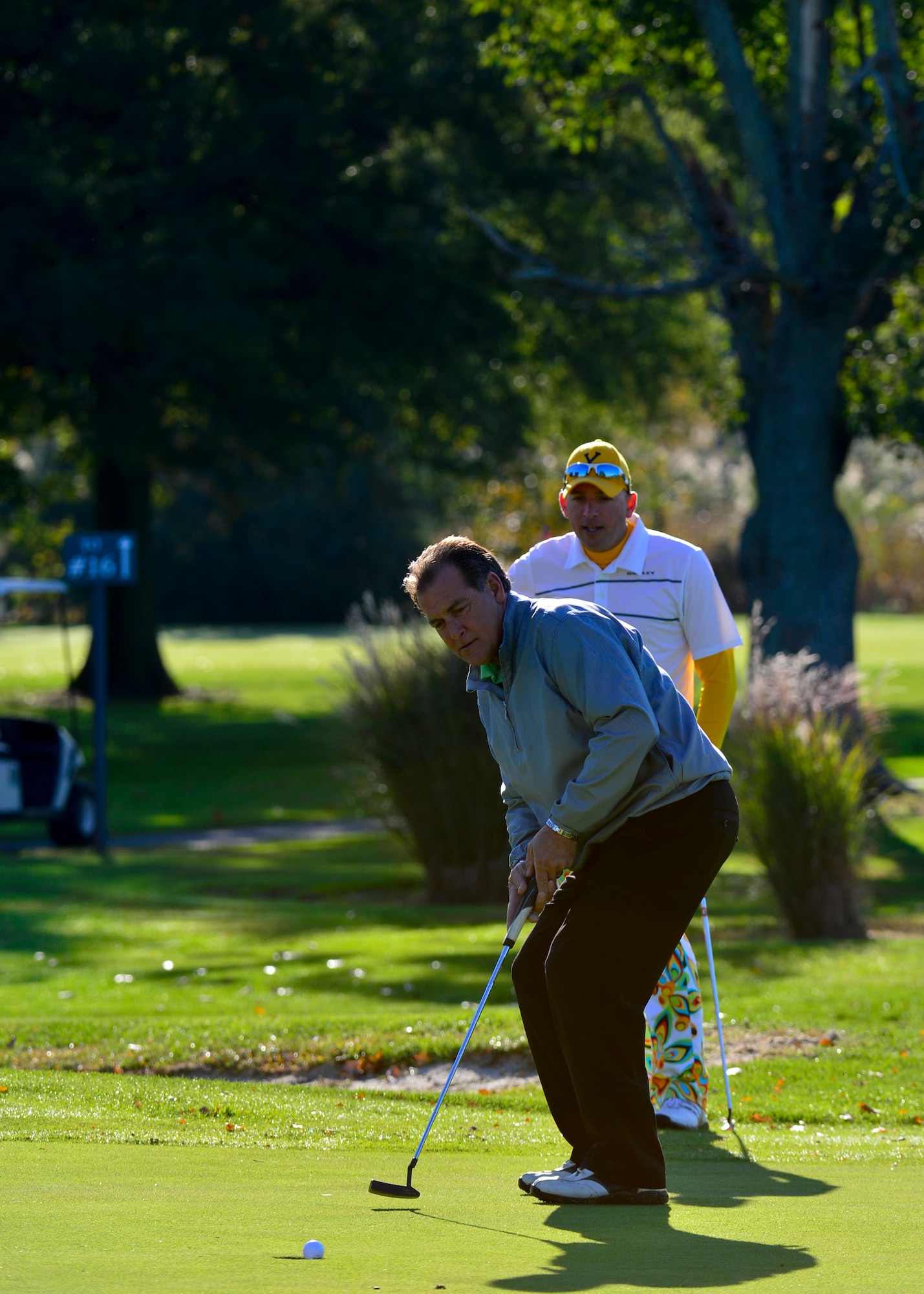Lt. Col. Donald Tasker, 436th Force Support Squadron commander, rear, watches Greg Newman, 436th Aircraft Maintenance Squadron honorary commander, as he sinks a putt during the 2015 Fall Bluesuiters Golf Tournament Oct. 16, 2015, at Eagle Creek Golf Course on Dover Air Force Base, Del. The tournament is part of Dover AFB’s community outreach program and connects local civic and business leaders with Team Dover Airmen. (U.S. Air Force photo/Senior Airman William Johnson) 