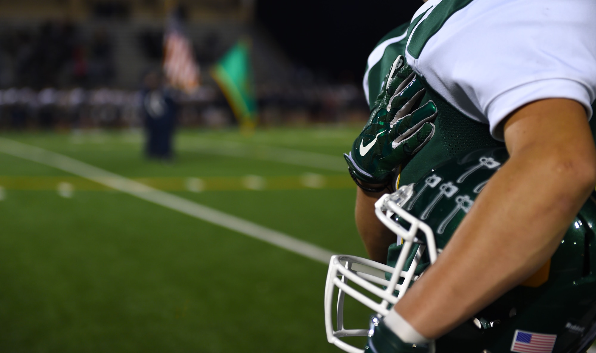 A Clover Park High School football team player puts his hand over his heart during the National Anthem and presentation of the colors prior to the Warrior’s game against River Ridge High School Oct. 16, 2015 in Lakewood, Wash. The Warriors recognized three McChord Airmen for their service to others as a part of their desire to honor “warriors” of the community. (U.S. Air Force photo/Senior Airman Naomi Griego)