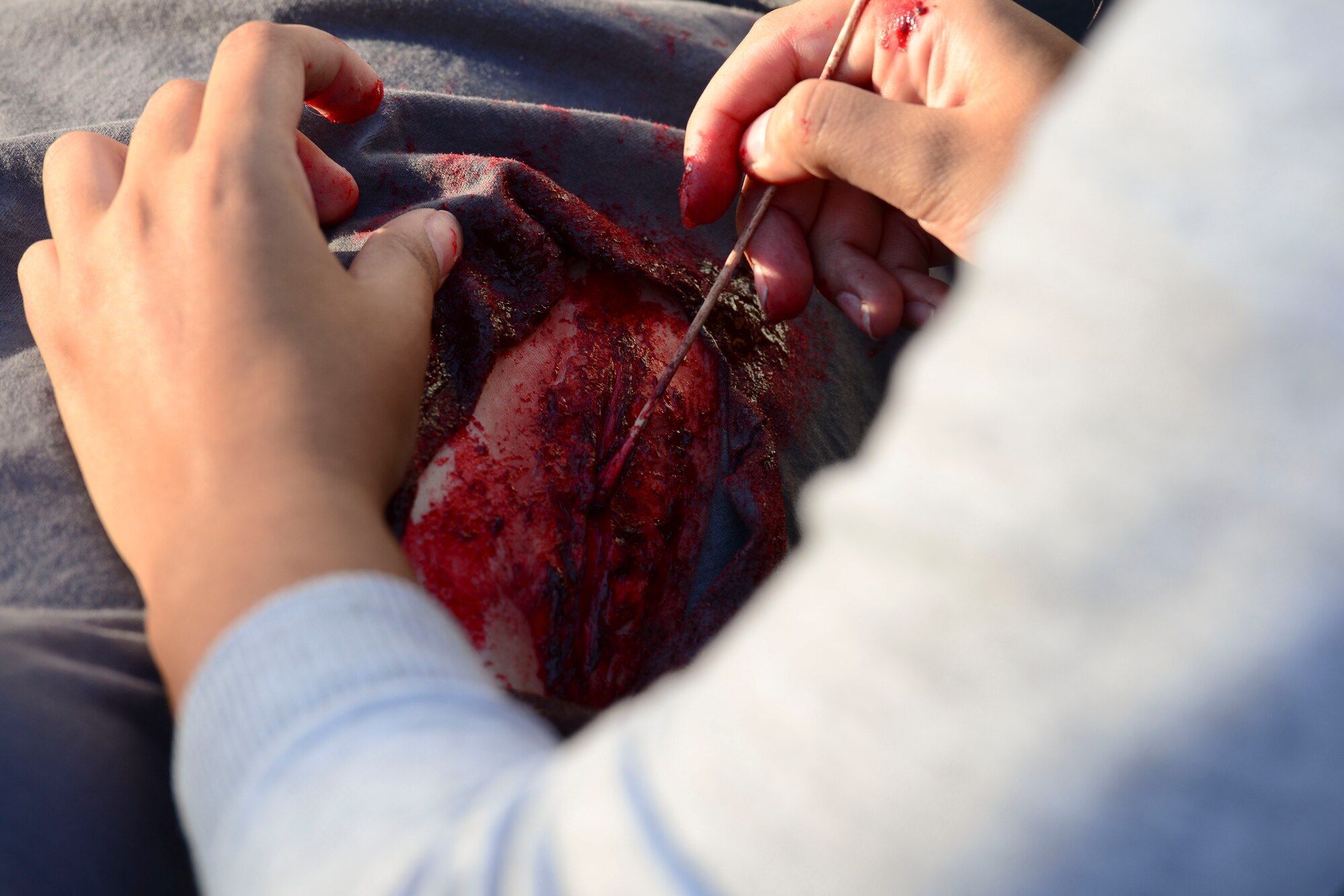U.S. Air Force Senior Airman Gloria Alqubaisi, 633rd Medical Group medical technician, perfects a moulage application on an exercise victim during a medical mass casualty exercise at Langley Air Force Base, Va., Oct. 15, 2015. Volunteers are applied moulage to simulate injuries for medical Airmen participating. (U.S. Air Force photo by Staff Sgt. Ciara Gosier/Released)