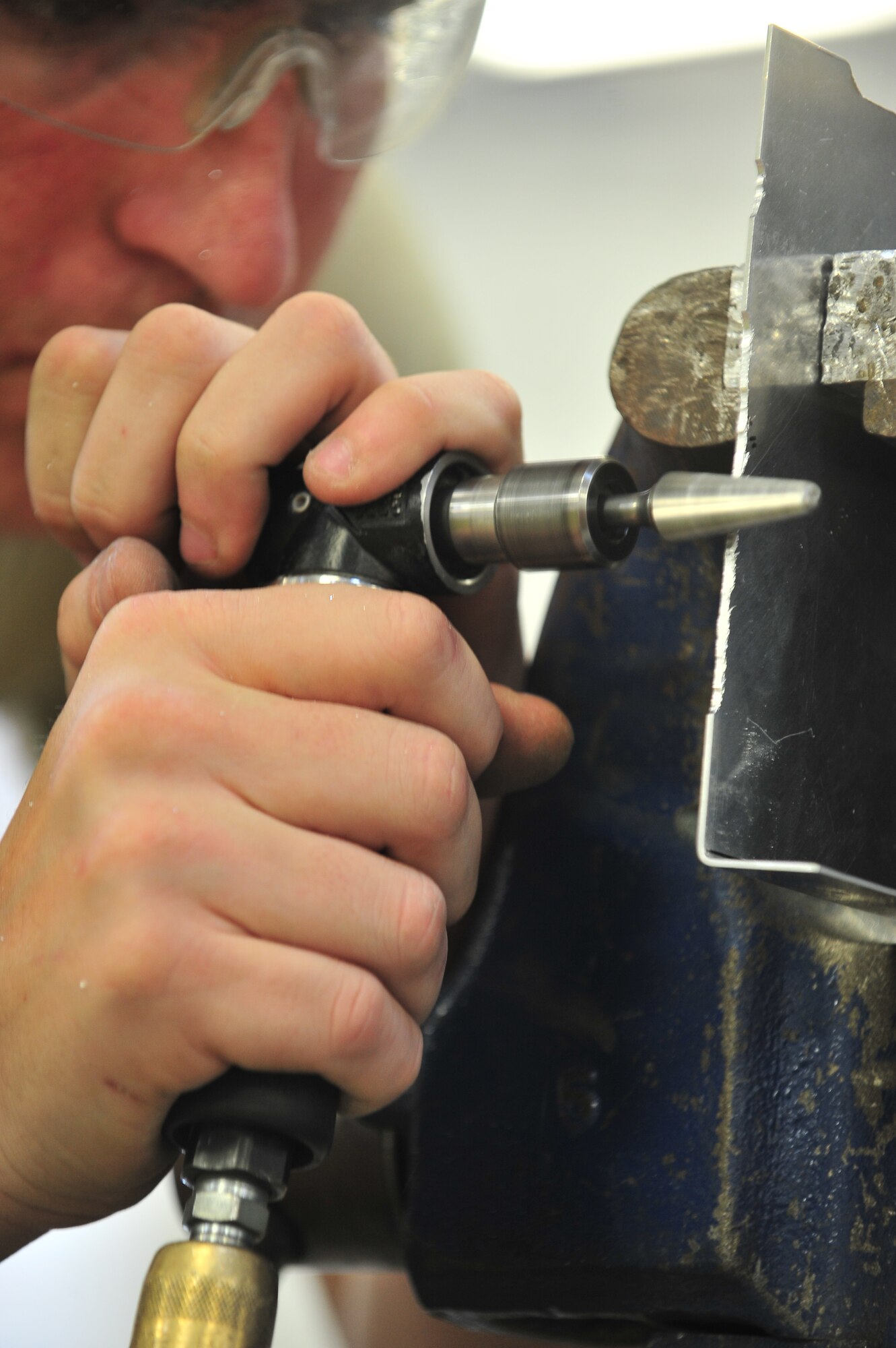 Senior Airman Johnathan Hilliker, 5th Maintenance Squadron aircraft structural maintenance journeyman, grinds the edge of a piece of metal at Minot Air Force Base, N.D., Oct. 14, 2015. Hilliker shaped the piece to fit on a classified materials safe box which is stored in the aircraft. (U.S. Air Force photo/Senior Airman Stephanie Morris)
