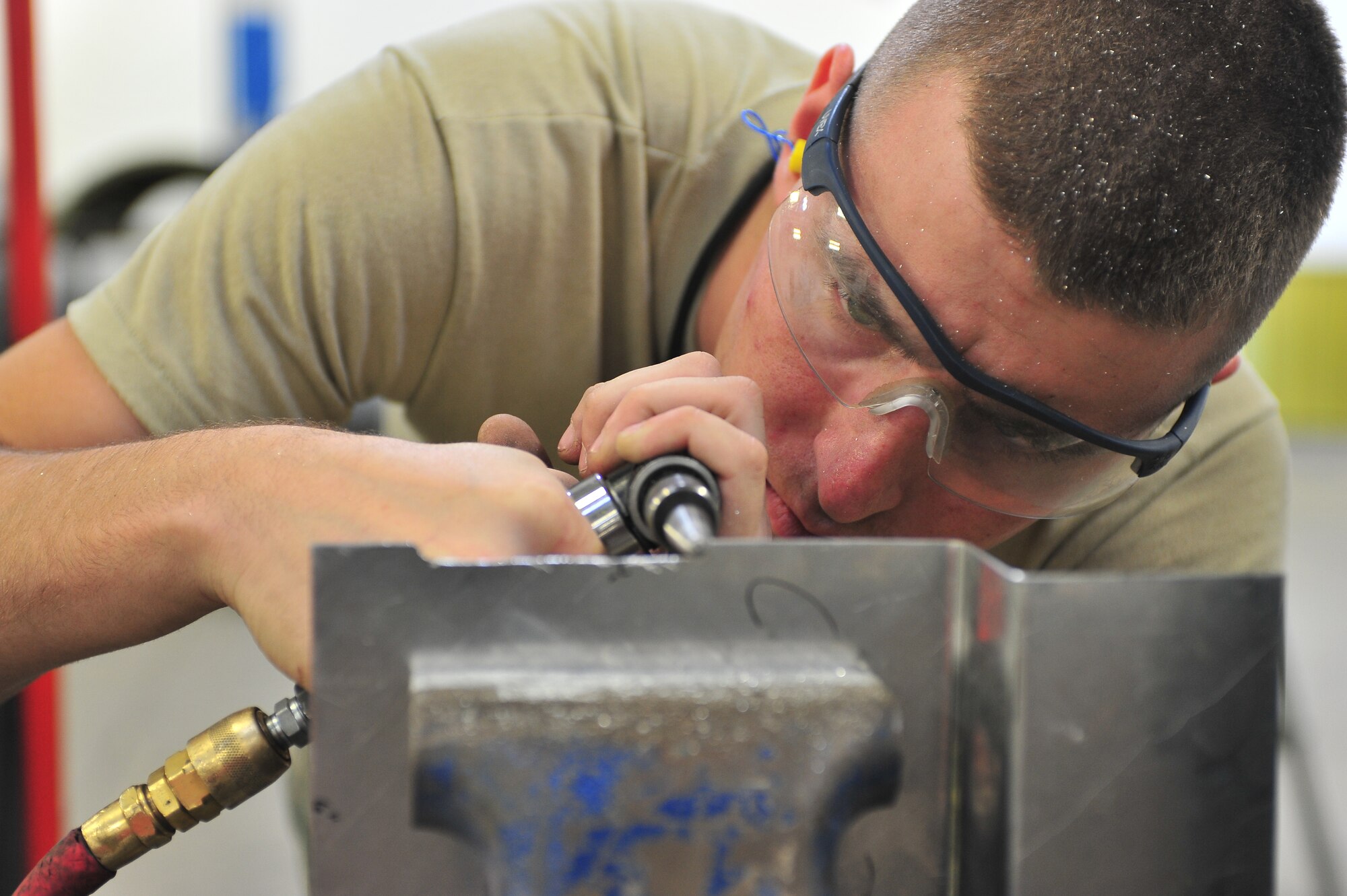 Senior Airman Johnathan Hilliker, 5th Maintenance Squadron aircraft structural maintenance journeyman, grinds the edge of a piece of metal at Minot Air Force Base, N.D., Oct. 14, 2015. Hilliker shaped the piece to fit on a classified materials safe box which is stored in the aircraft. (U.S. Air Force photo/Senior Airman Stephanie Morris)