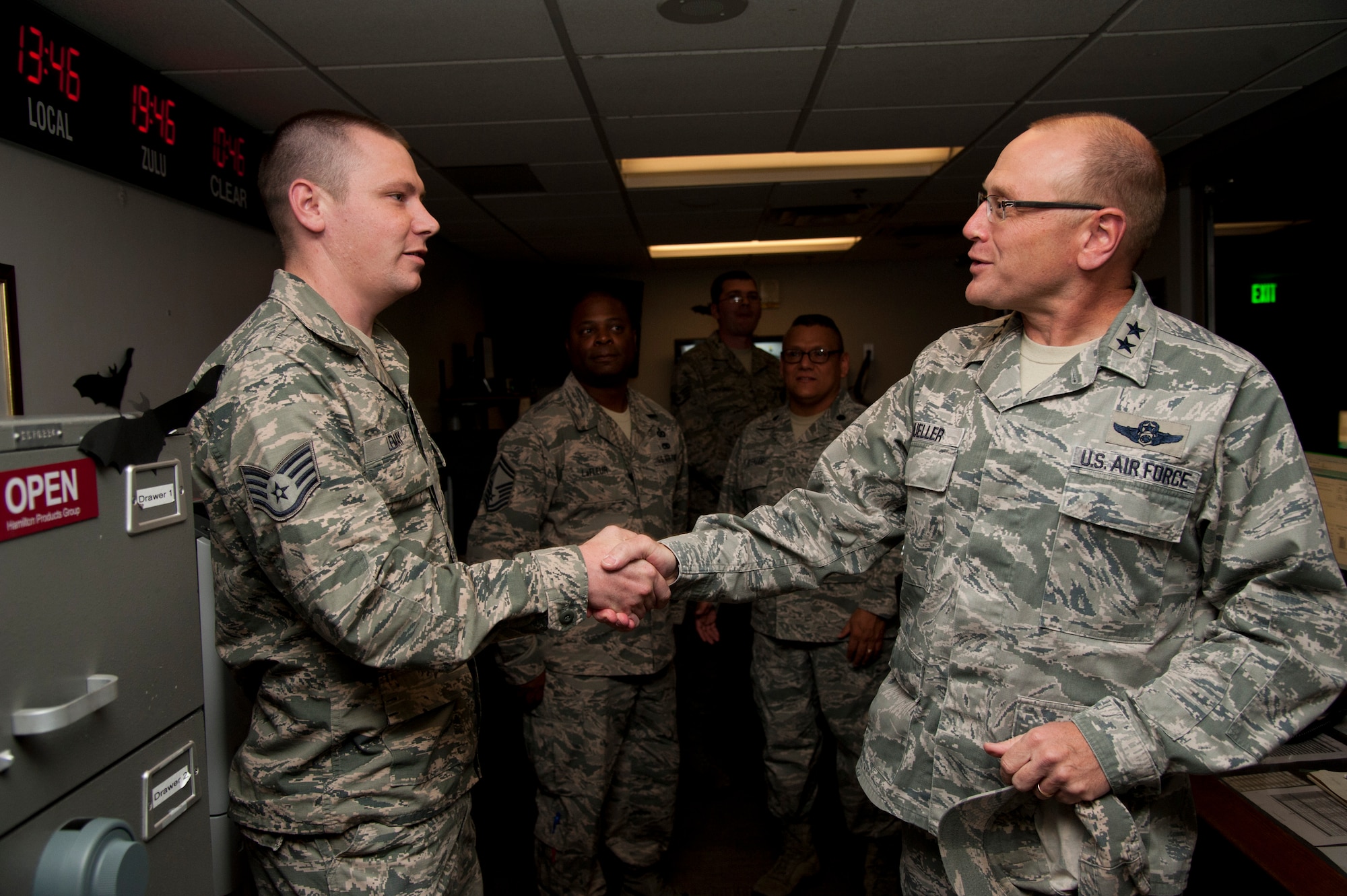 PETERSON AIR FORCE BASE, Colo. - Maj. Gen. Andrew Mueller, Headquarters U.S. Air Force chief of safety and Air Force Safety Center commander, coins Staff Sgt. Curtis LeMay, 302nd Airlift Wing emergency action controller, for his stellar work with the installation notification warning system, Oct. 13, 2015. Mueller visited Team Pete Airmen in their work centers during his first stop on a tour of all the major commands and their installations as the new chief of safety offering his vision of “preserving combat capability.” (U.S. Air Force photo by Senior Airman Tiffany DeNault) 