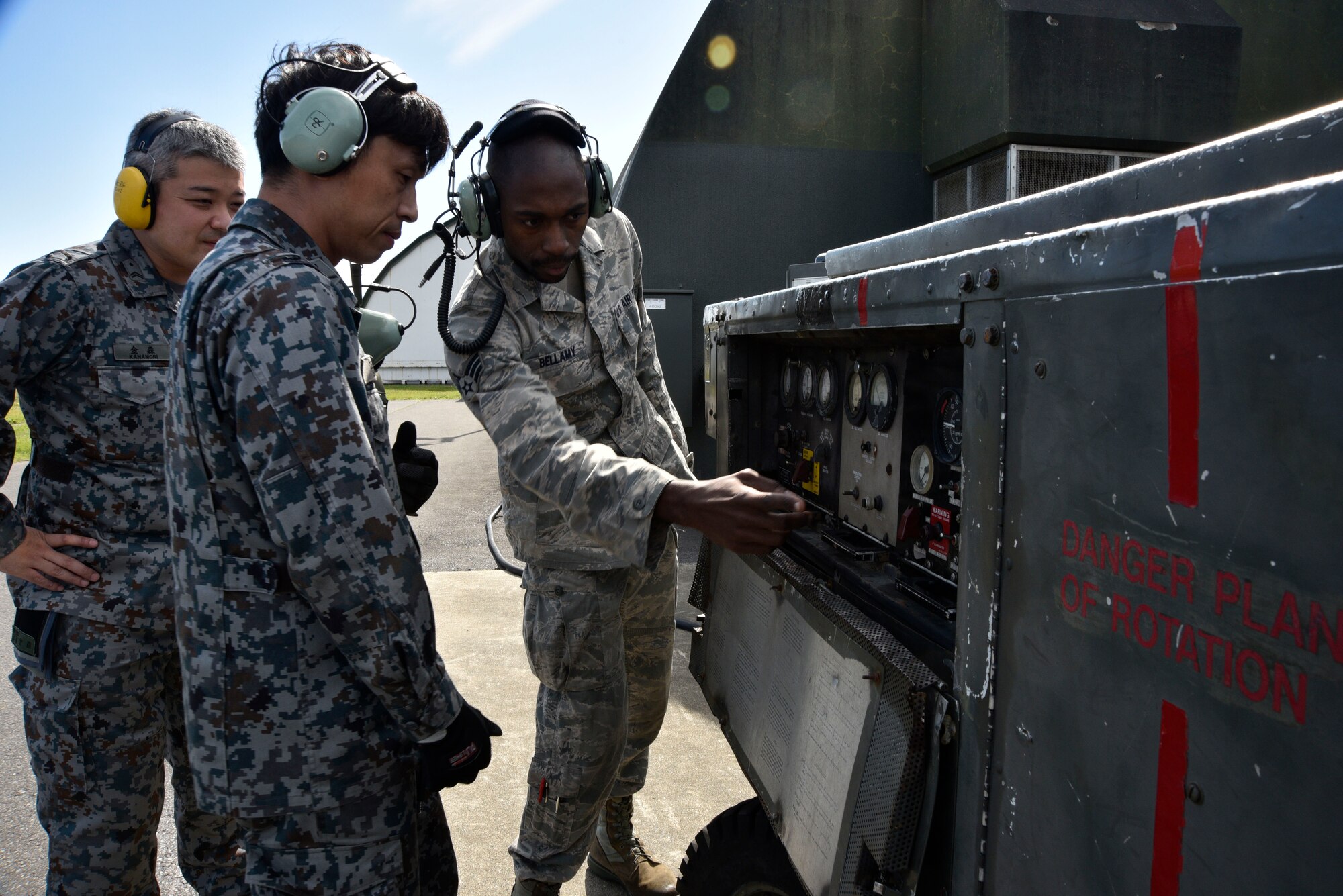 U.S. Air Force Senior Airman Revel Bellamy, 35th Aircraft Maintenance Squadron avionics journeyman, explains the control panel settings of a portable air conditioning unit to Japan Air Self-Defense Force Staff Sgt. Yuuichi Sato and Tech. Sgt. Yuya Kanamori at Misawa Air Base, Japan, Oct. 1, 2015. As part of a bilateral exchange program, 11 JASDF maintainers from the 8th Air Wing were paired with 35th Maintenance Group Airmen from diverse job specialties. (U.S. Air Force photo by Senior Airman Jose L. Hernandez-Domitilo/Released)