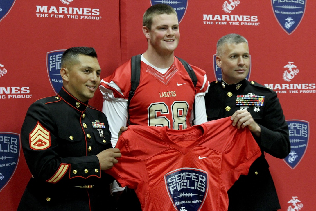 Logan Bathke a high school senior at Orange Lutheran High School in Orange, Calif., poses with Maj. James Dollard, Marine Corps Recruiting Orange County commanding officer, and Staff Sgt. Noe Santana, a Marine Corps Recruiting Orange County canvassing recruiter, after being presented a Semper Fidelis All-American Bowl game jersey Oct. 9, 2015. Bathke was selected to participate in the SFAAB, scheduled for Jan. 3 in Carson, Calif. Bathke plays offensive tackle for the Orange Lutheran Lancer’s varsity football team and will continue to showcase his athletic abilities next year at the University of Oregon.