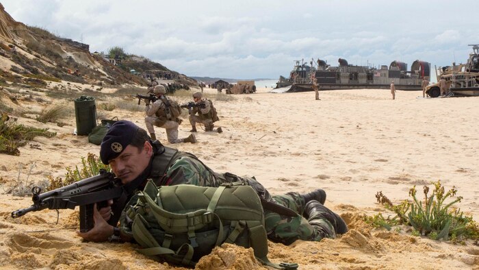 A Portuguese Marine holds security at Pinheiro Da Cruz, Praia Da Raposa beach, Portugal, while participating in a combined amphibious assault exercise, Oct. 20, 2015, during Trident Juncture 15. Trident Juncture is a NATO-led exercise designed to certify NATO response forces and develop interoperability among participating NATO and partner nations. 