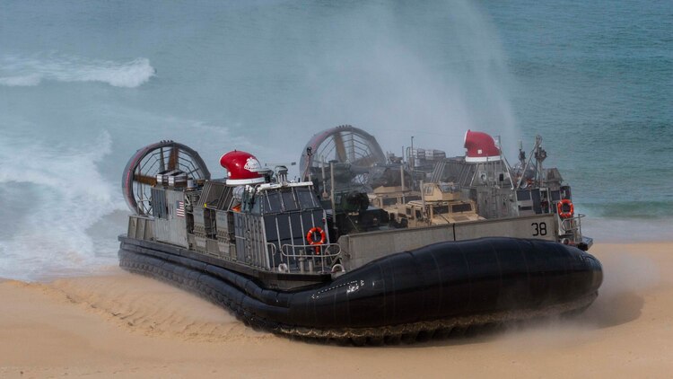 A landing craft air-cushion, or LCAC, transporting U.S. Marines, with the 26th Marine Expeditionary Unit and Portuguese Marines from the USS Arlington (LPD-24), Kearsarge Amphibious Ready Group (KSGARG) lands at Pinheiro Da Cruz, Praia Da Raposa beach, Portugal, to participate in a combined amphibious assault exercise, Oct. 20, 2015, during Trident Juncture 15. Trident Juncture is a NATO-led exercise designed to certify NATO response forces and develop interoperability among participating NATO and partner nations.