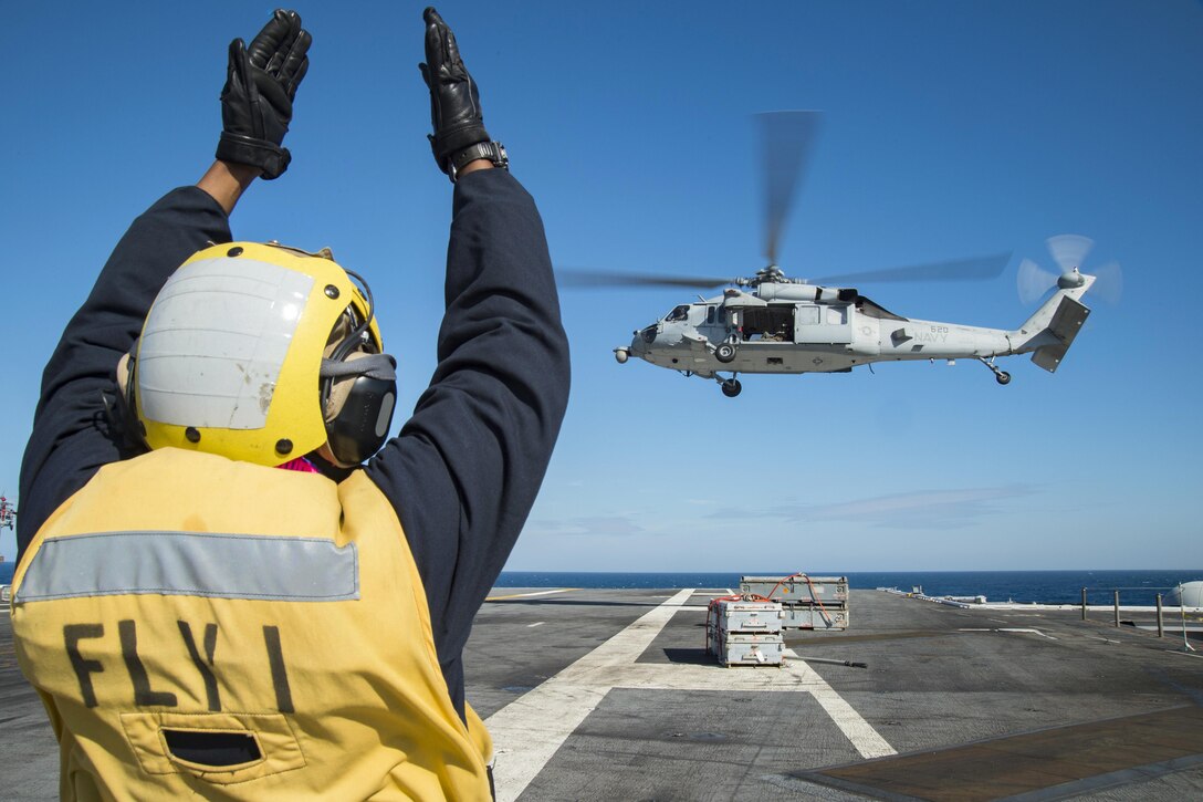 U.S. Navy Petty Officer 2nd Class Keyonnia Cook directs an MH-60S Sea Hawk helicopter as it delivers ammunition to the aircraft carrier USS Dwight D. Eisenhower in the Atlantic Ocean, Oct. 13, 2015. The supplies came from dry cargo and ammunition ship USNS Robert E. Peary during an ammunition replenishment. U.S. Navy photo by Seaman Anderson W. Branch