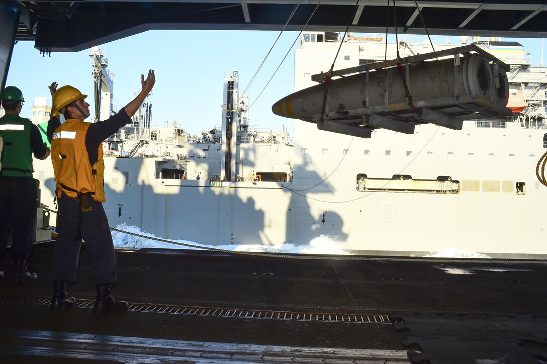 U.S. Navy Petty Officer 2nd Class C.J. Mentley uses hand signals to  communicate with crew during an ammunition replenishment for the aircraft carrier USS Dwight D. Eisenhower in the Atlantic Ocean, Oct. 13, 2015. The supplies were provided by the dry cargo and ammunition ship USNS Robert E. Peary. U.S. Navy photo by Seaman Anderson W. Branch