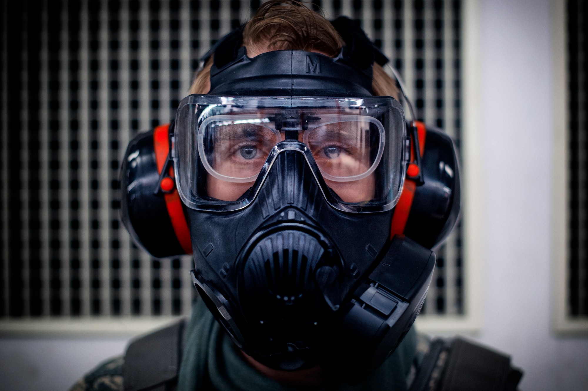 Senior Airman Dylan Fagan, 374th Security Forces Squadron armorer, dons a gas mask before performing M-4 Carbine qualifying at Yokota Air Base, Japan, Oct. 8, 2015. The qualifying course test Airmen on their ability to fire an M-4 carbine from several positions: prone, standing and while wearing a gas mask. (U.S. Air Force photo by Airman 1st Class Delano Scott/Released)