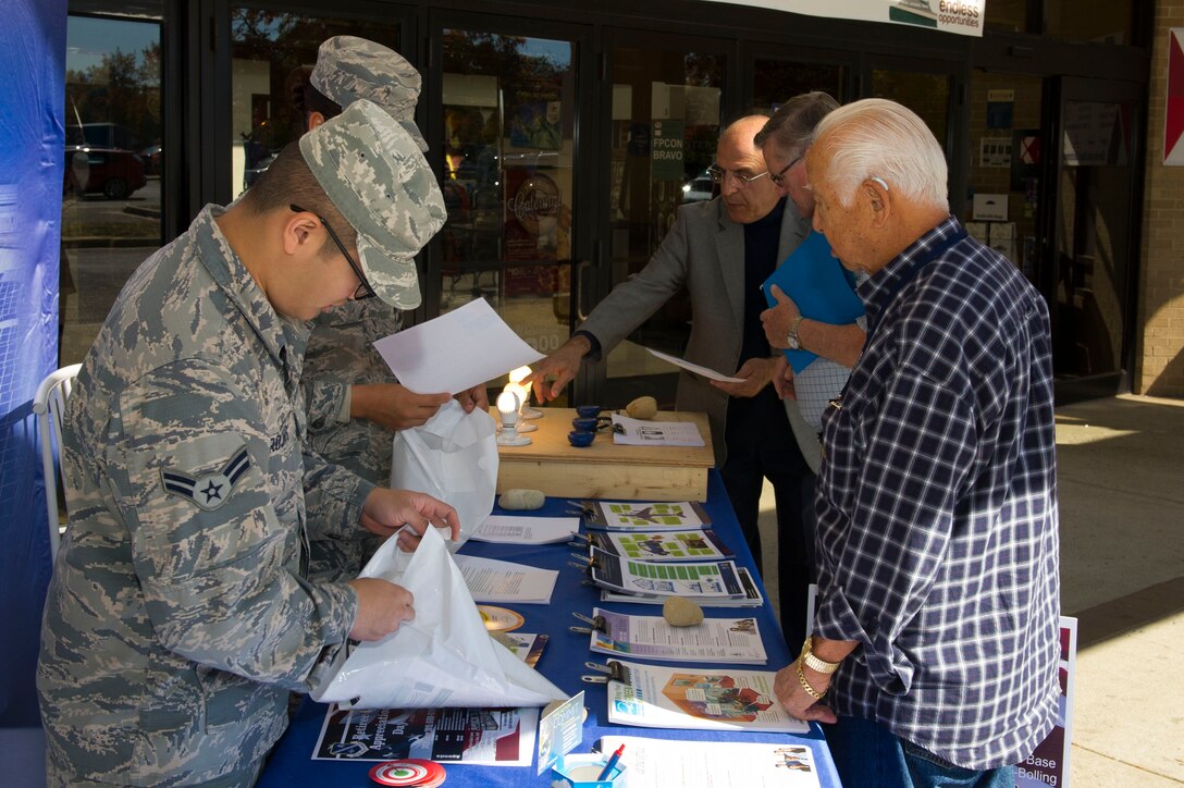 Joint Base Andrews community members visit the Energy Action Day booth, Oct. 21, 2015, at the Base Exchange on Joint Base Andrews, Md. The booth, as part of Energy Awareness Month, informed community members of cost saving tips on conserving energy and included a demonstration and resources on how to do so. (U.S. Air Force photo by Senior Airman Dylan Nuckolls/Released)