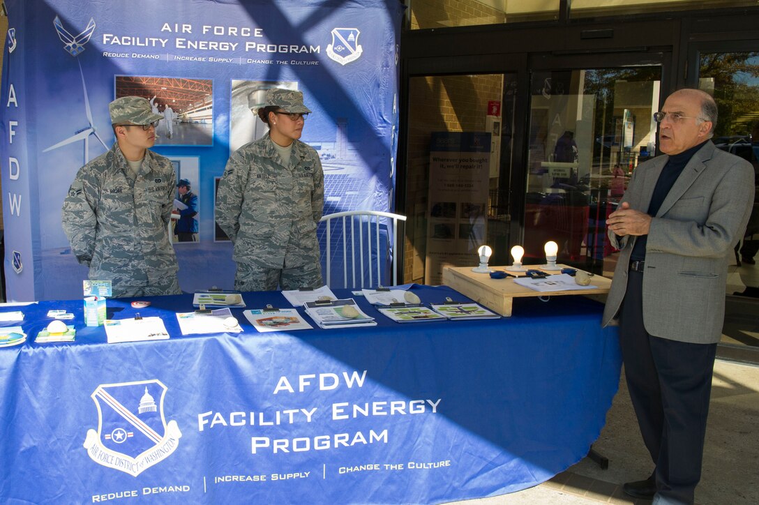 Airman 1st Class Johnneil Rojas, LaLynn Antell, 11th Civil Engineer Squadron, wait with Mohammad Alikhani, base energy manager, for an audience at the Energy Action Day booth, Oct. 21, 2015, at the Base Exchange on Joint Base Andrews, Md. The booth, as part of Energy Awareness Month, informed community members of cost saving tips on conserving energy and included a demonstration and resources on how to do so. (U.S. Air Force photo by Senior Airman Dylan Nuckolls/Released)